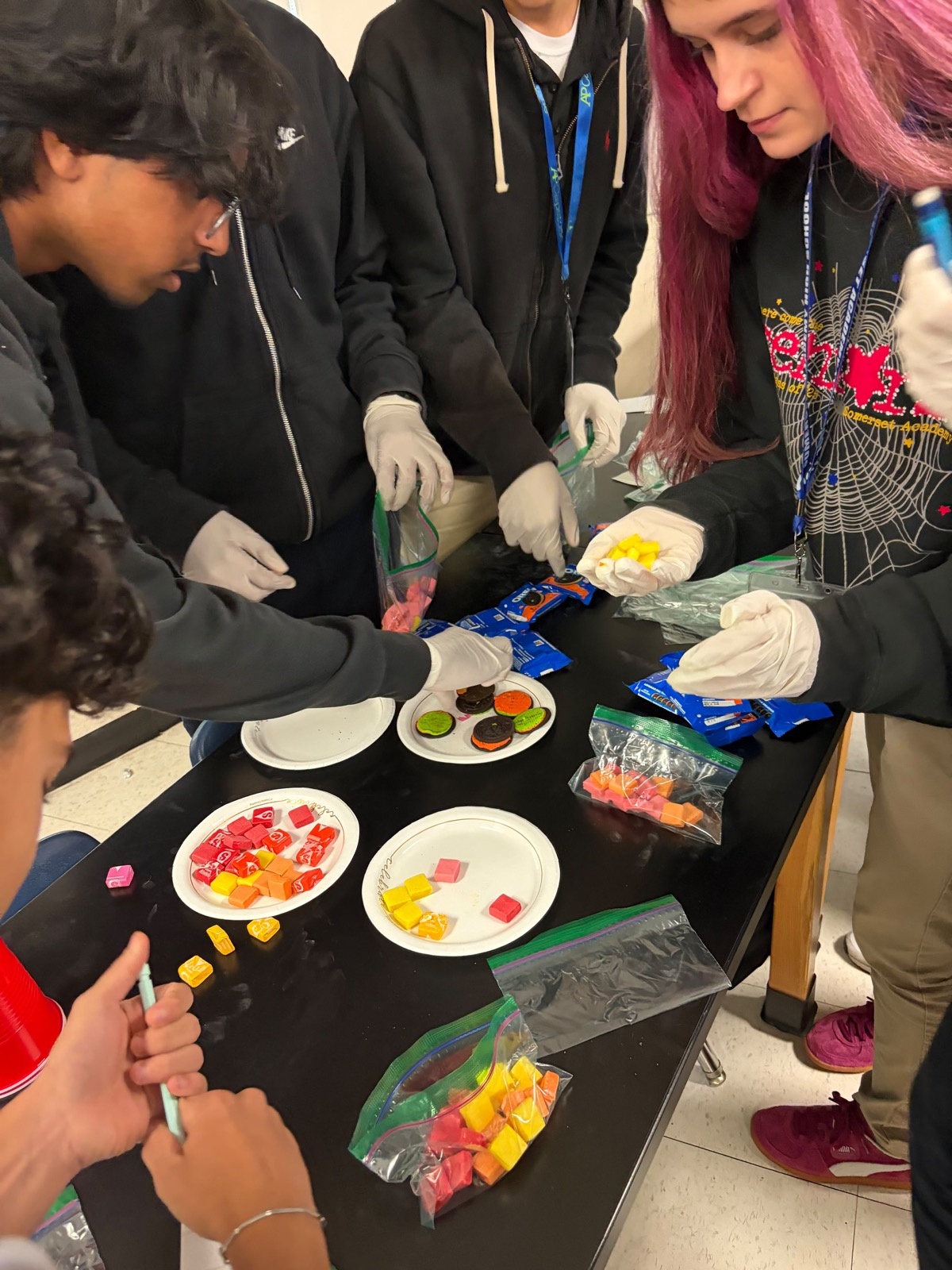 Students in gloves sorting colored candy on a lab table during the Industrial Engineering Workshop